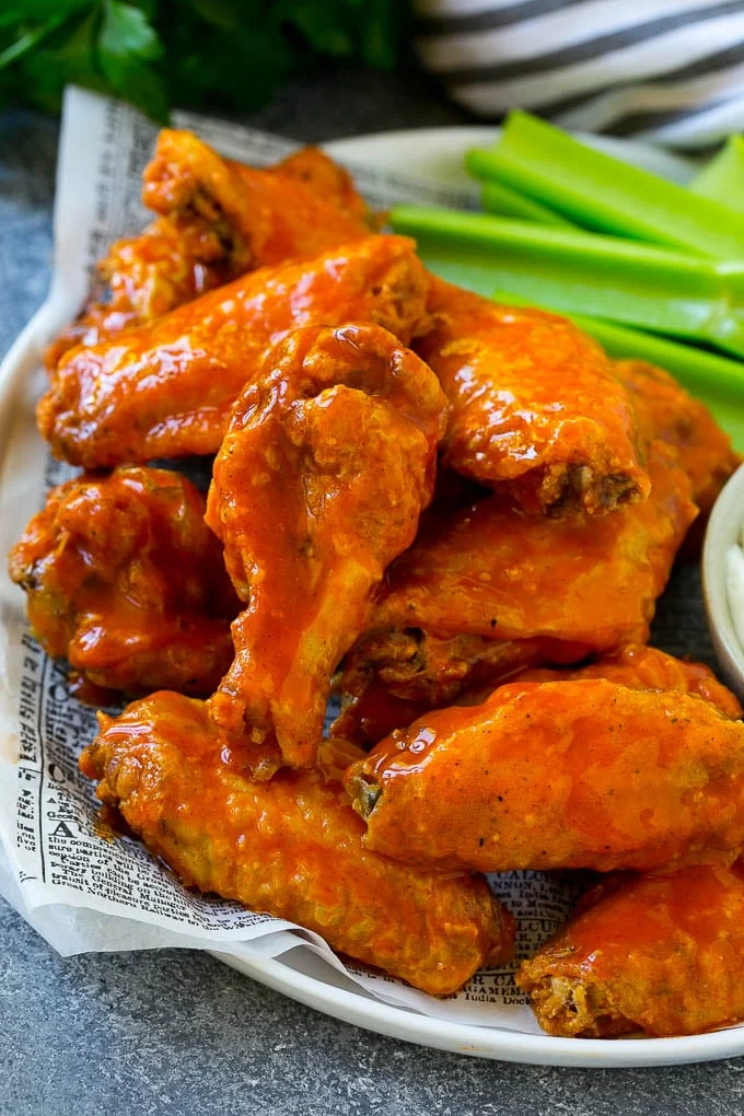 Platter of saucy buffalo chicken wings with celery and dipping sauce